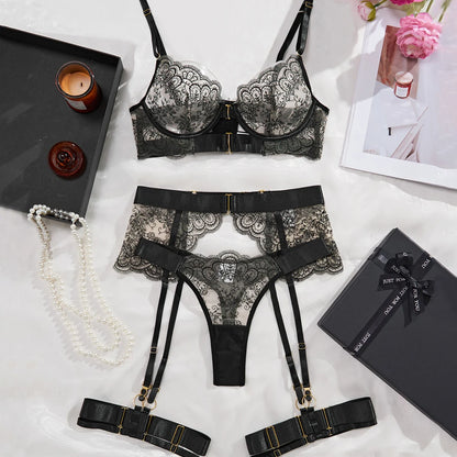 Black lace lingerie set with garters on a light surface with decorative items.