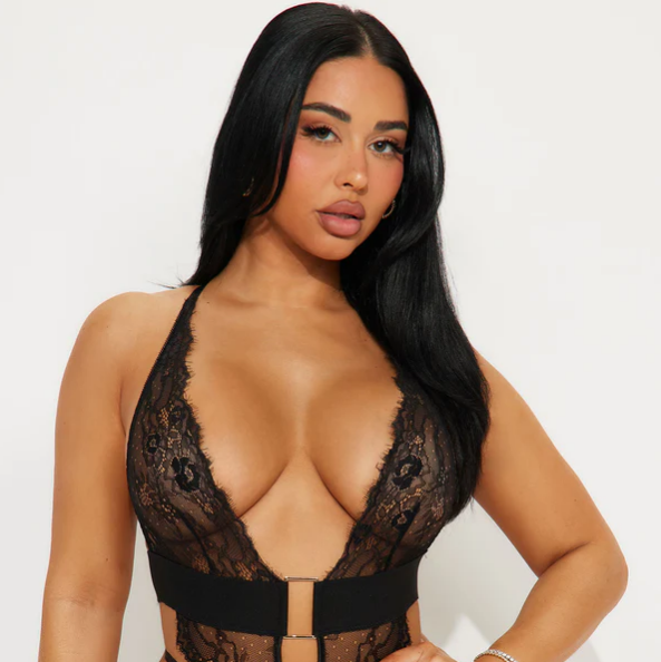Woman wearing a black lace lingerie set against a white background